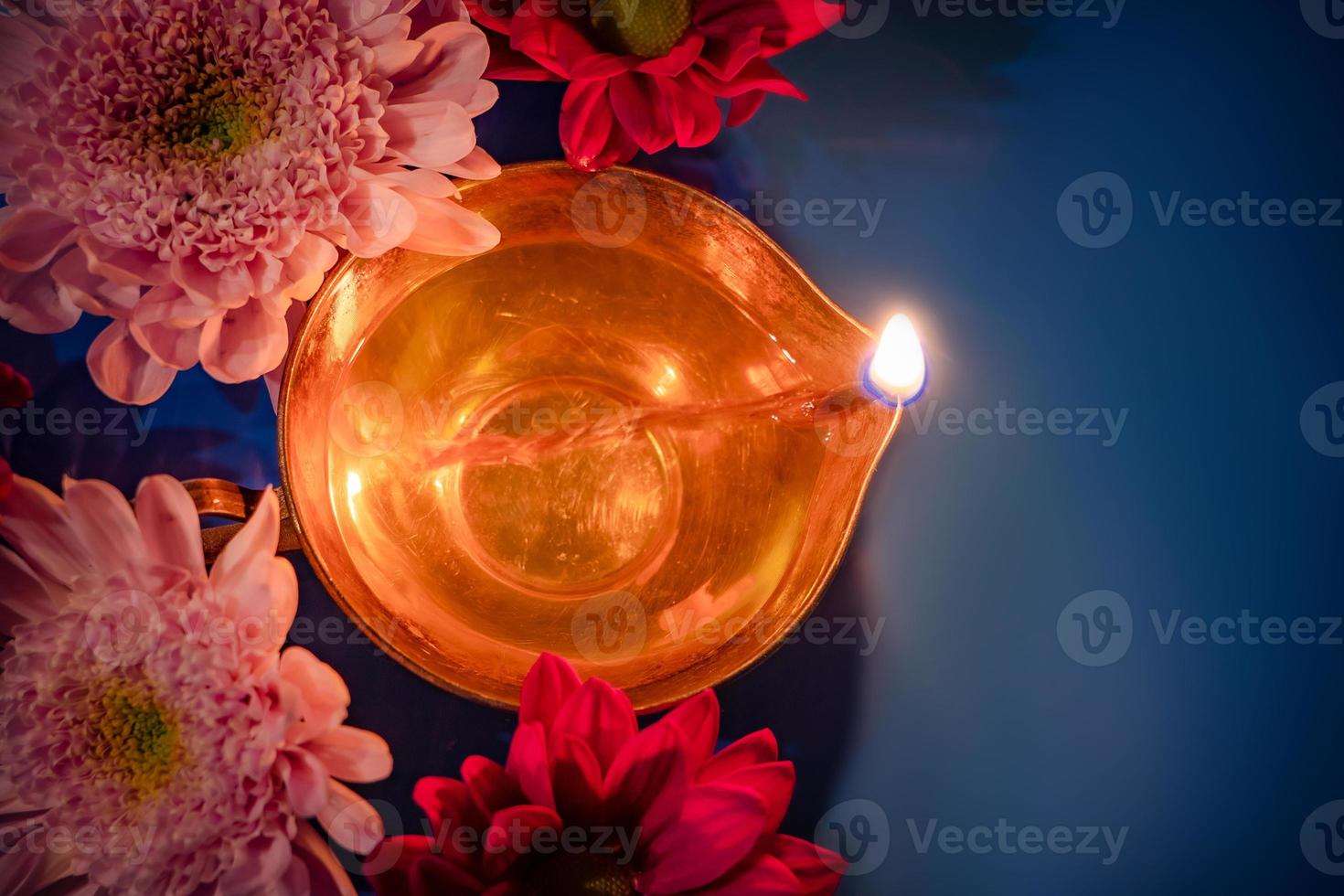 Celebrating Indian festival of light Diwali. Close-up of traditional diya oil lamps and flowers on blue background. photo