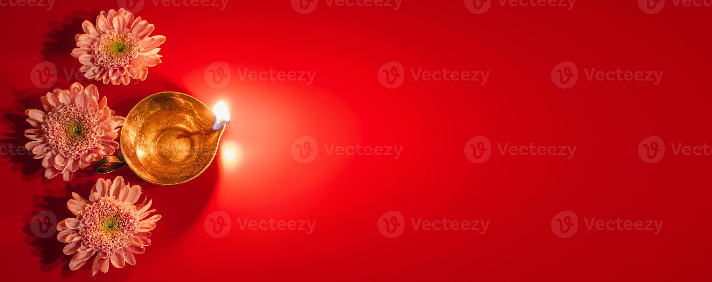 Happy Diwali. Diya oil lamp and flowers on red background. Traditional Hindu celebration. Religious holiday of light. photo