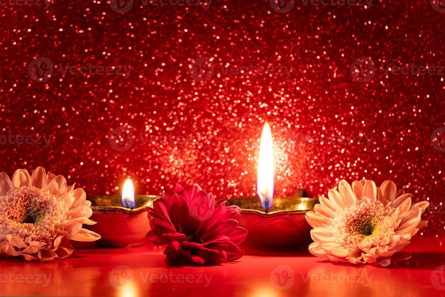 Happy Diwali. Burning diya oil lamps and flowers on red glittering background. Celebrating the traditional Indian festival of light. photo