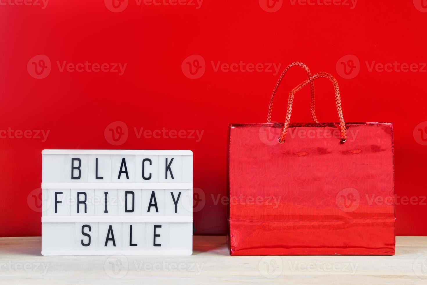 Black Friday sale concept. Gift bag and lightbox on red background. photo