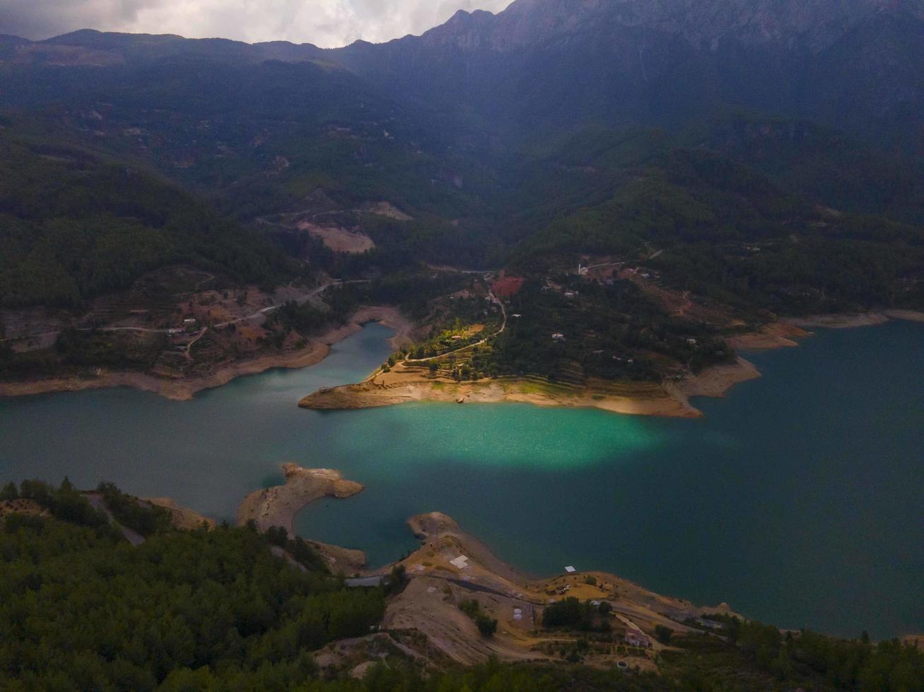 Turquoise water in a mountain forest lake with pine trees. Aerial view of blue lake and green forests. View on the lake between mountain forest. Over crystal clear mountain lake water. Fresh water photo