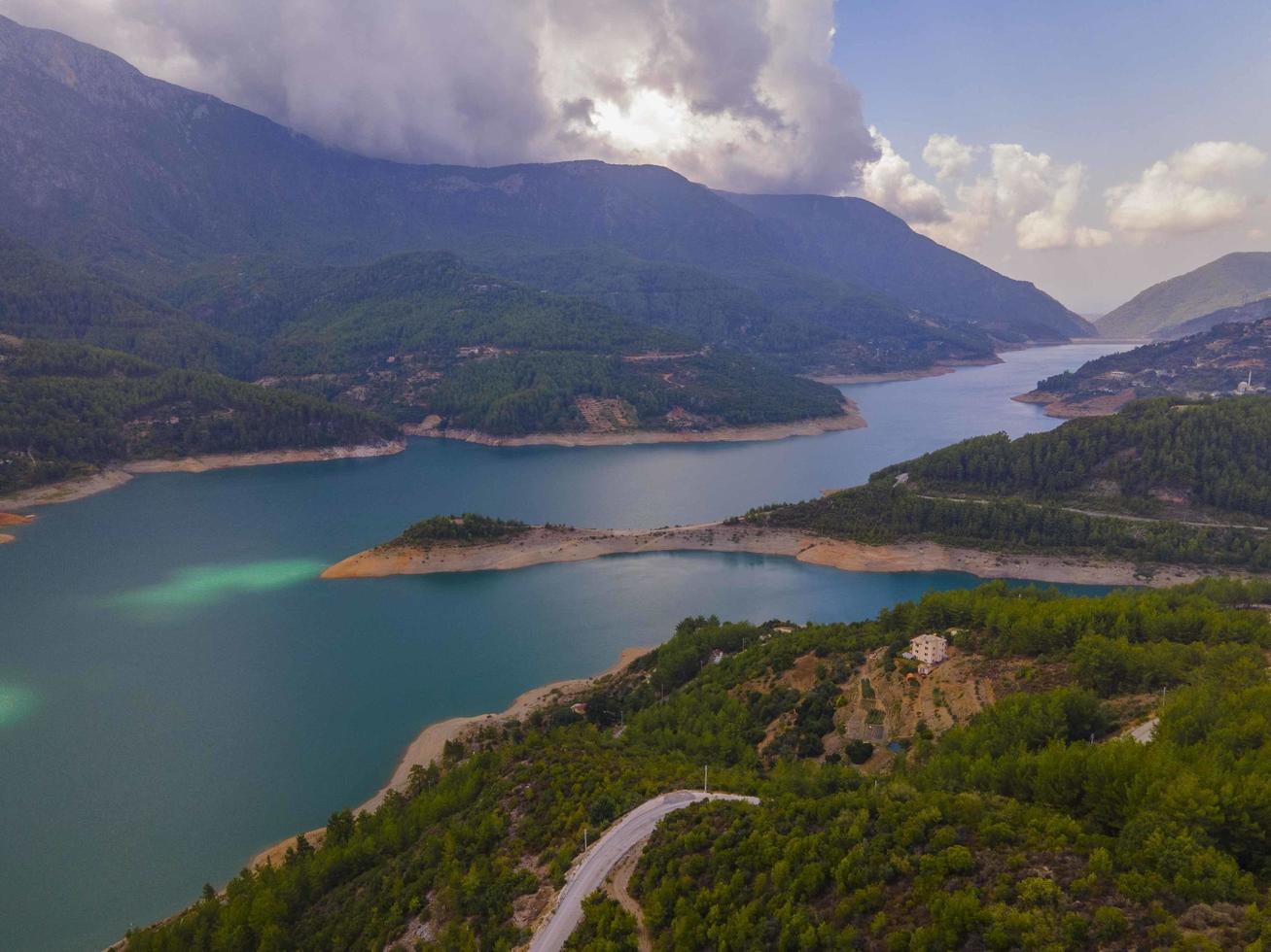 Turquoise water in a mountain forest lake with pine trees. Aerial view of blue lake and green forests. View on the lake between mountain forest. Over crystal clear mountain lake water. Fresh water photo