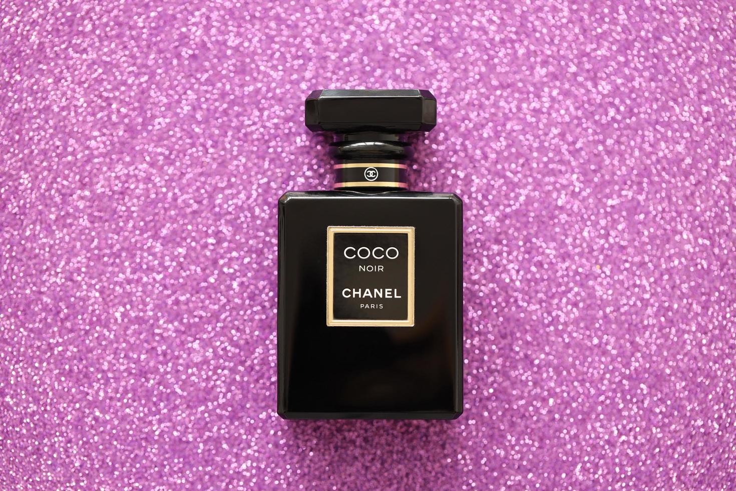 TERNOPIL, UKRAINE - SEPTEMBER 2, 2022 Coco Noir Chanel Paris worldwide famous french perfume black bottle on shiny glitter background in purple colors photo