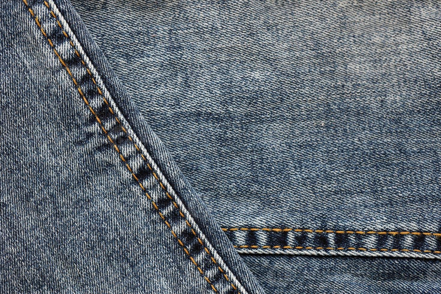Detailed abstract texture of dark blue denim cloth. Background image of old used denim trousers fabric photo