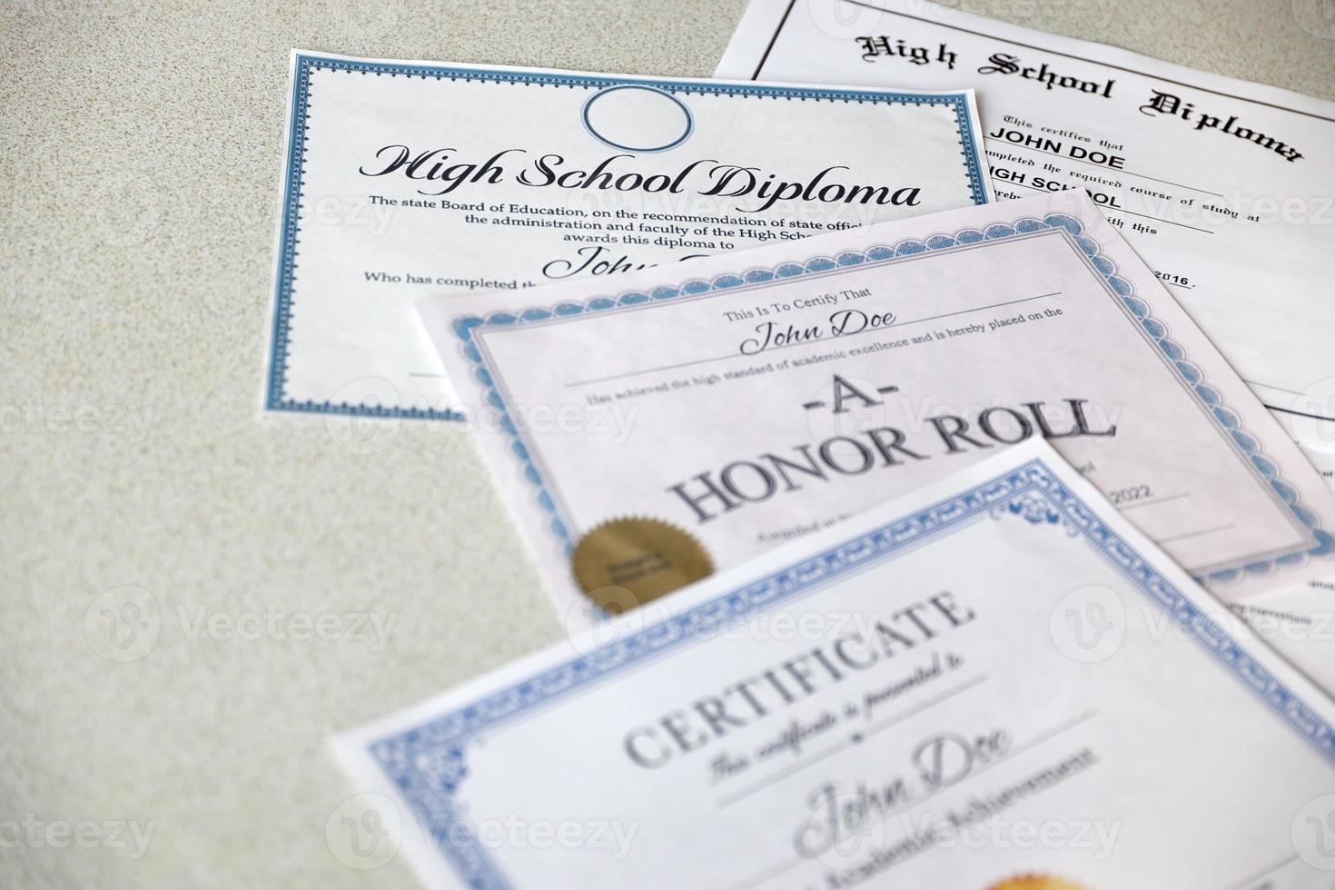 A honor roll recognition, certificate of achievement and high school diploma lies on table. Education documents photo