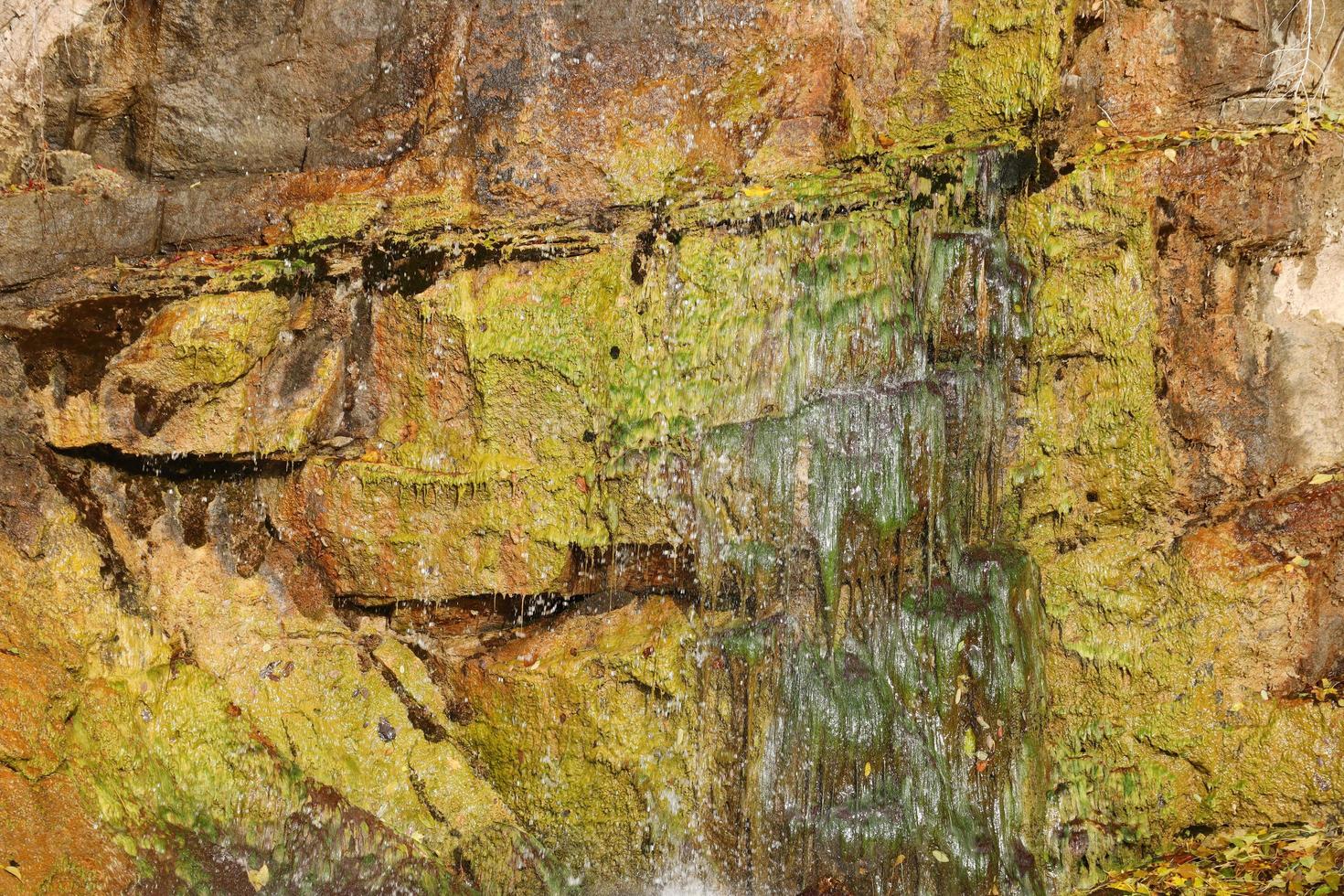 Waterfall among stones and trees. Close-up of boulders in water. Huge stones in green moss. Beautiful landscape of fast waterfall with small whirlpools photo