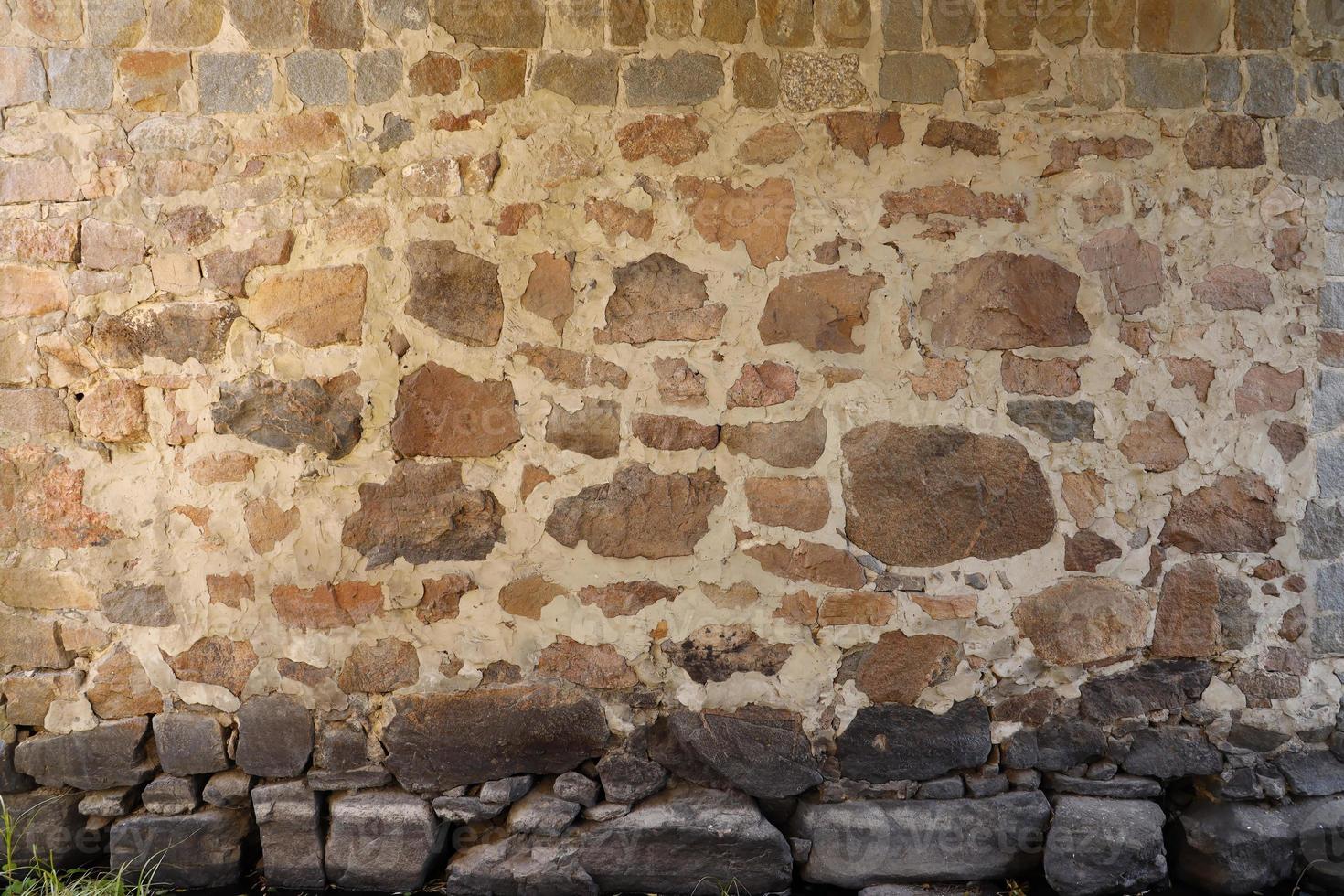 Texture of a stone wall with many big brown and grey stones armed with