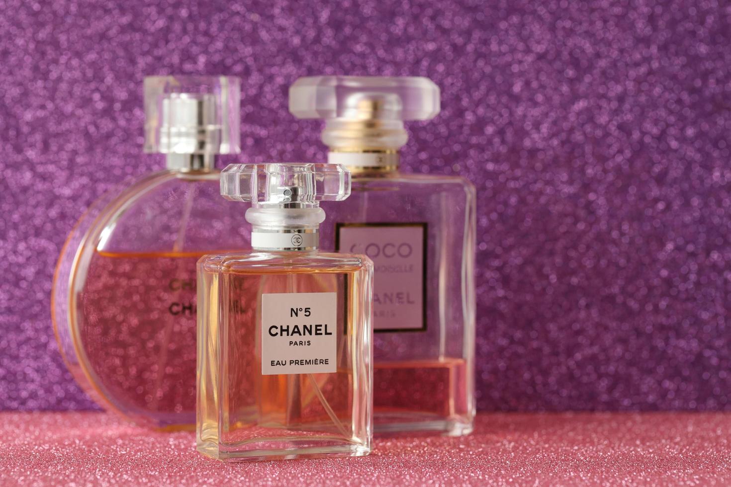 TERNOPIL, UKRAINE - SEPTEMBER 2, 2022 Chanel Number 5 Eau Premiere worldwide famous french perfume bottle among other perfumes on shiny glitter background in purple colors photo