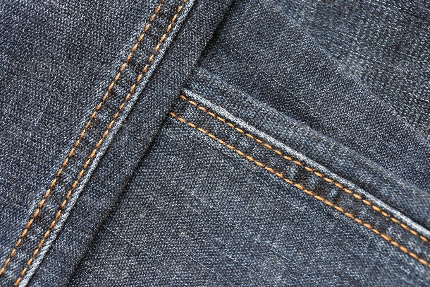 Detailed abstract texture of dark blue denim cloth. Background image of old used denim trousers fabric photo