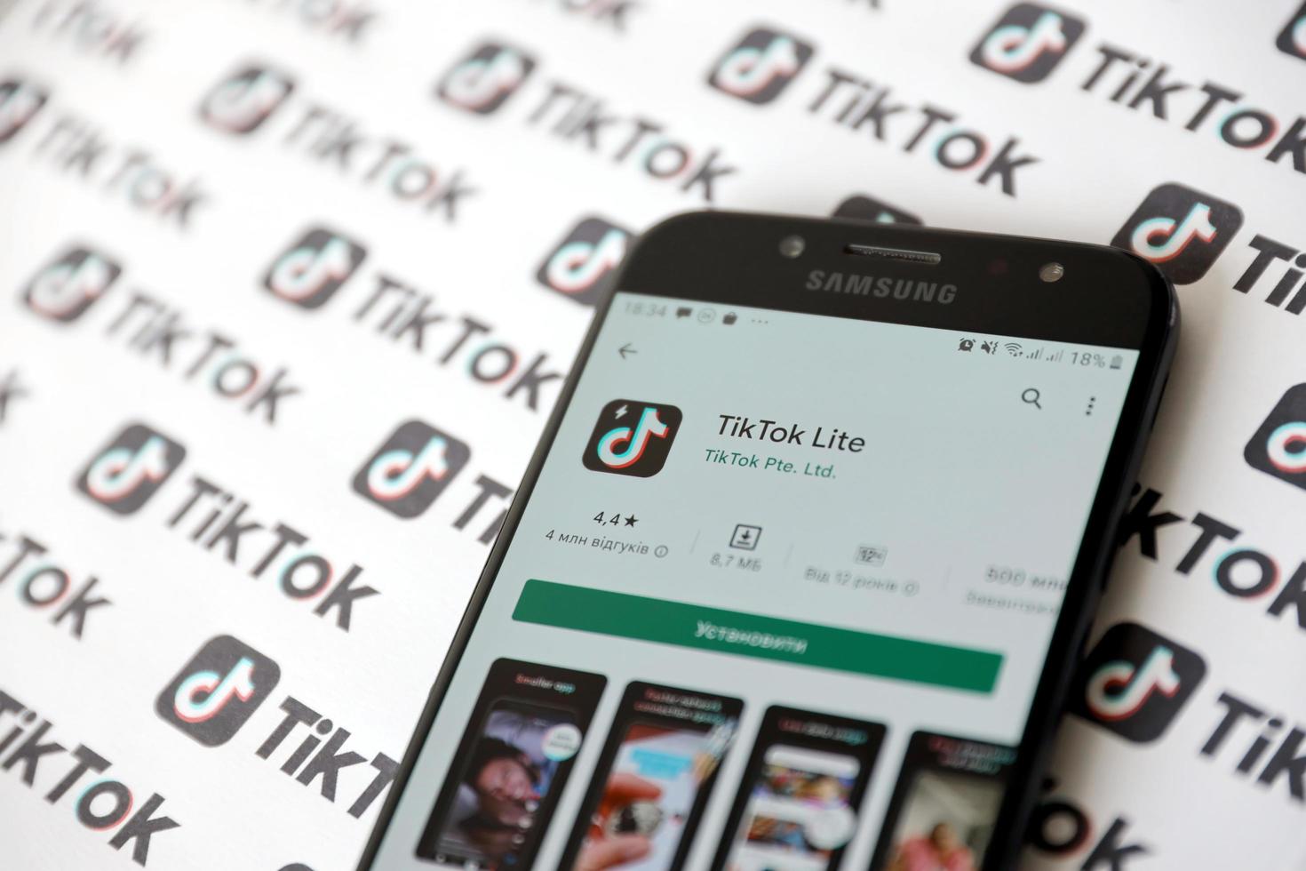 ternopil, ucrania - 2 de mayo de 2022 aplicación de teléfono inteligente tik tok en pantalla y muchos logotipos de tiktok impresos en papel. tiktok o douyin es un famoso servicio chino de alojamiento de videos de formato corto propiedad de bytedance foto