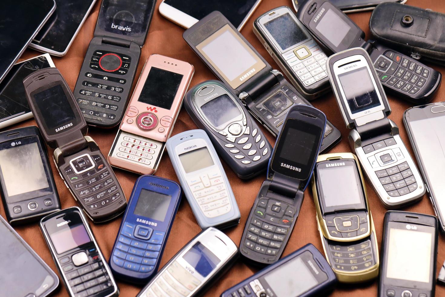 KHARKIV, UKRAINE - DECEMBER 16, 2021 Some old used outdated mobile phones from 90s-2000s period. Recycling electronics in the market photo