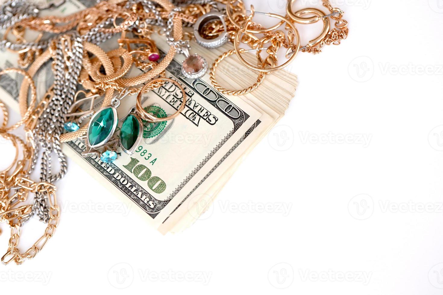 Many expensive golden and silver jewerly rings, earrings and necklaces with big amount of US dollar bills on white background. Pawnshop or jewerly shop photo