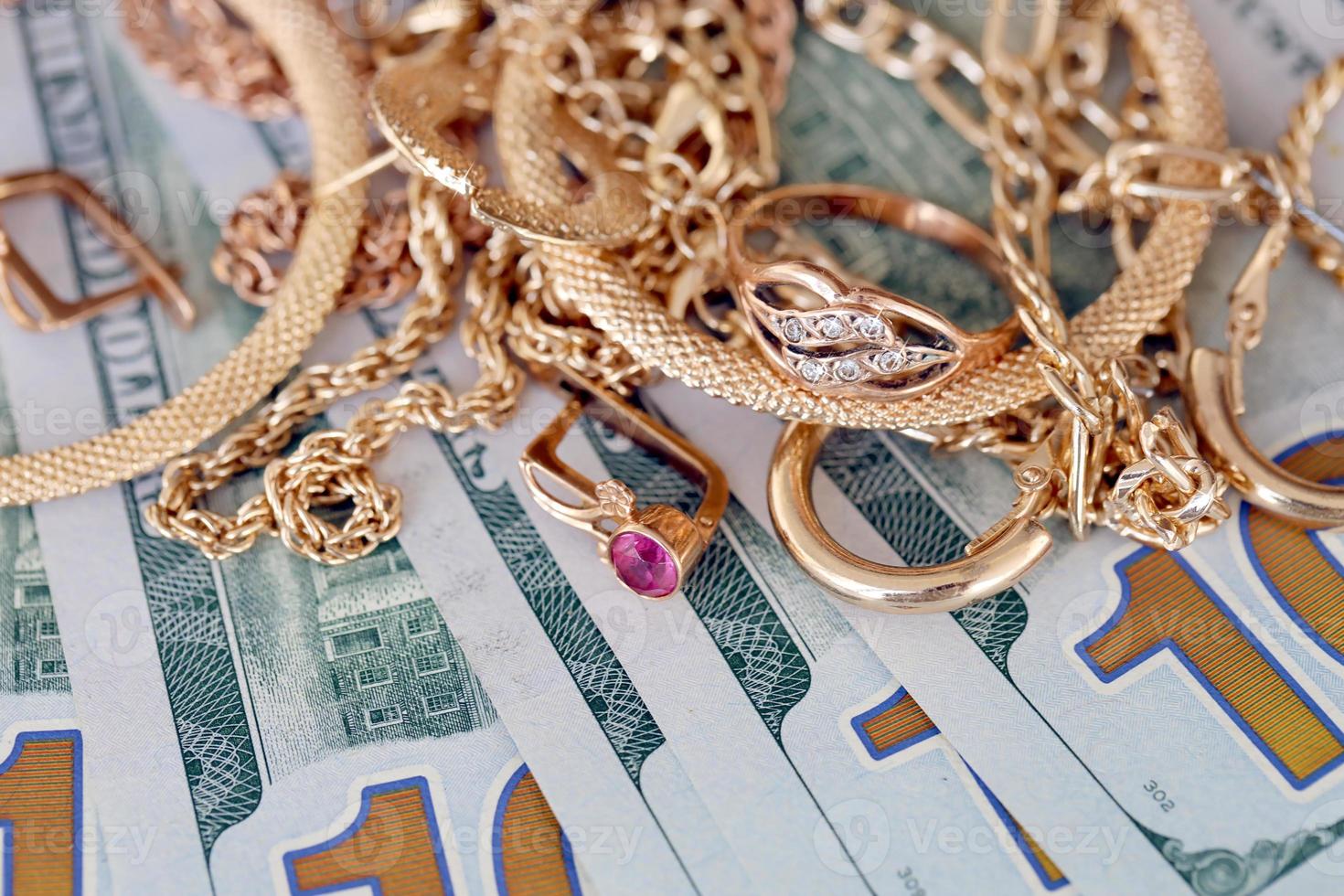 Many expensive golden jewerly rings, earrings and necklaces with big amount of US dollar bills on white background. Pawnshop or jewerly shop photo