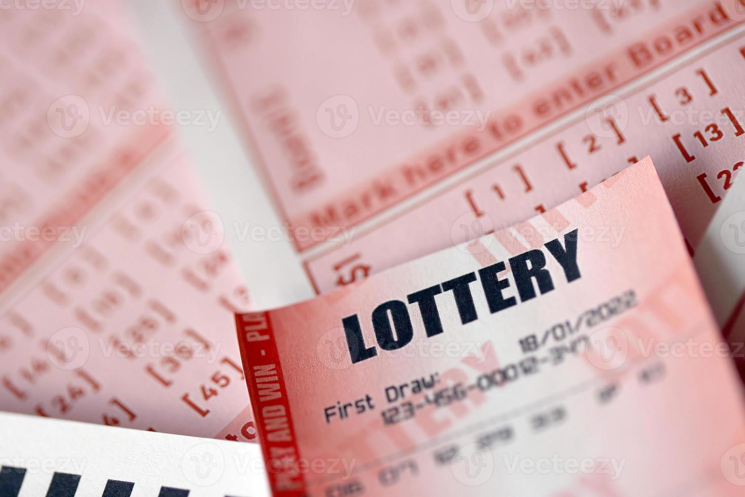 Red lottery ticket lies on pink gambling sheets with numbers for marking to play lottery. Lottery playing concept or gambling addiction. Close up photo