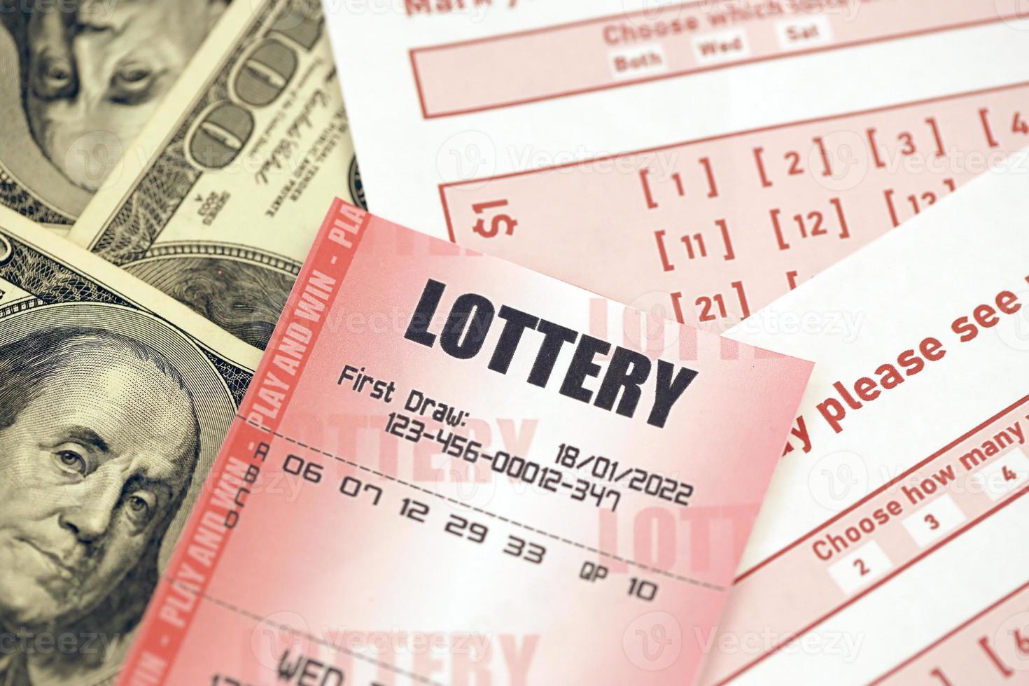 Red lottery ticket lies on pink gambling sheets with numbers for marking on big amount of hundred dollar bills. Lottery playing concept or gambling addiction. Close up photo