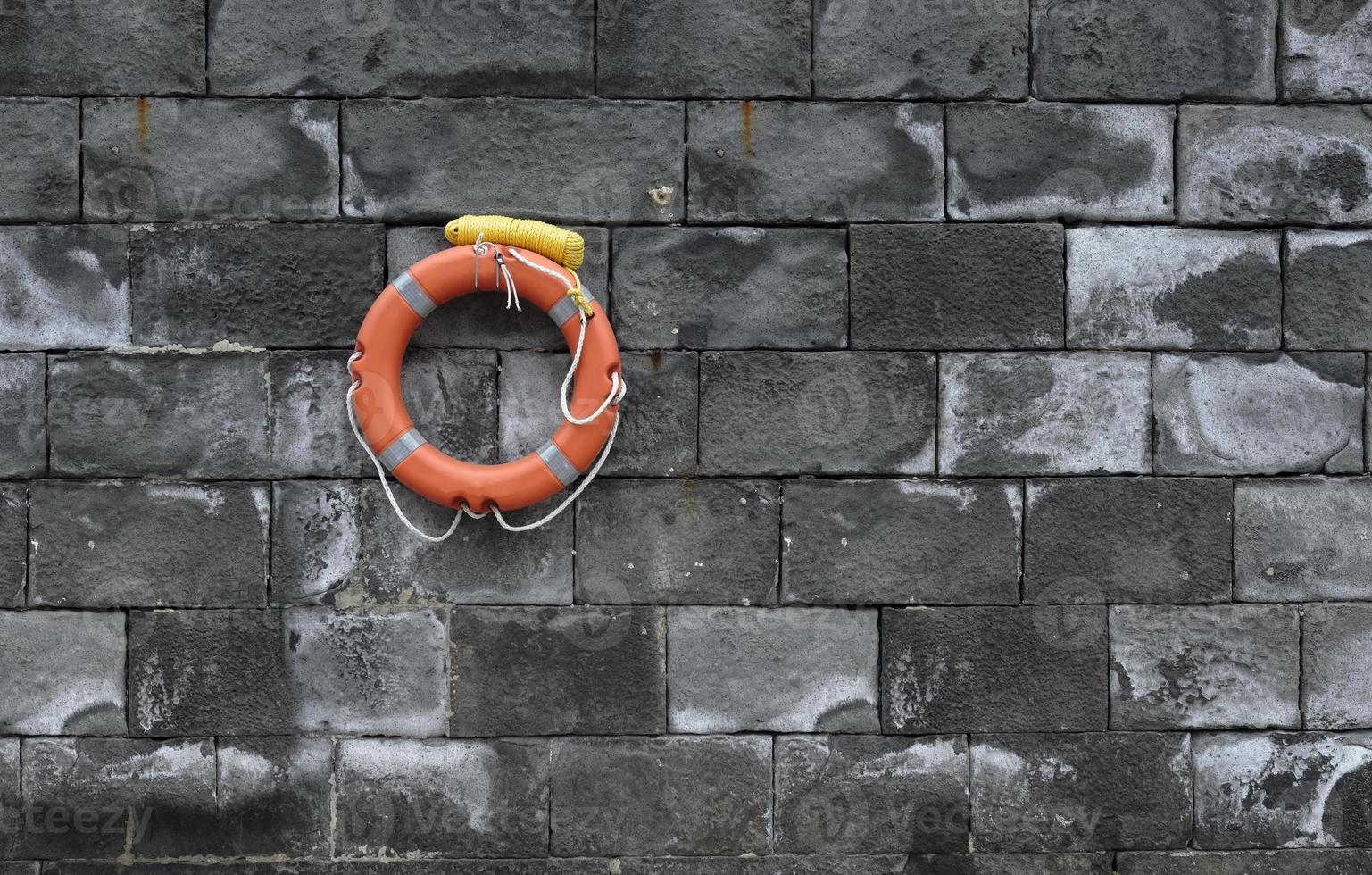 Lifesaver on a stone wall at the harbor photo