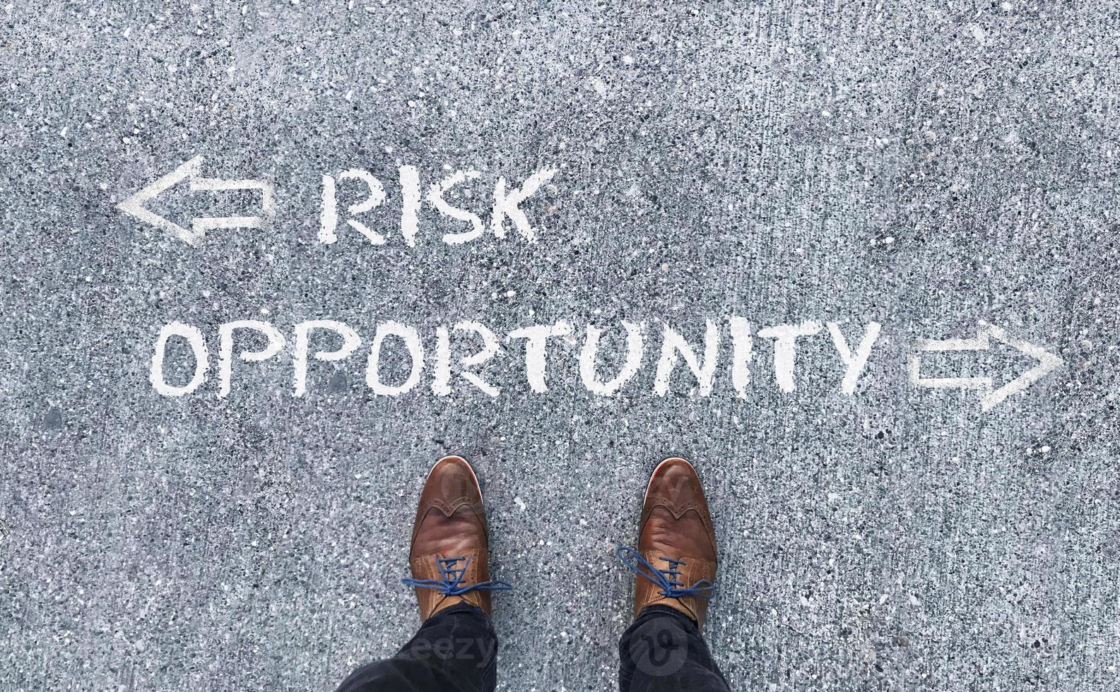 Top view on a man standing in front of the words Risk and Opportunity with arrows pointing to the left and right side of the picture photo