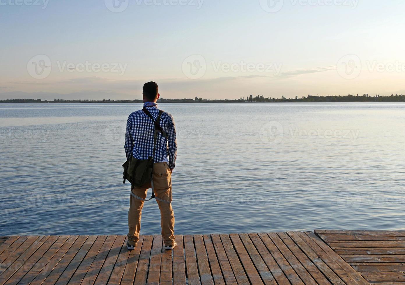 hombre de pie en la orilla del lago issyk kul en Kirguistán en las horas de la tarde foto