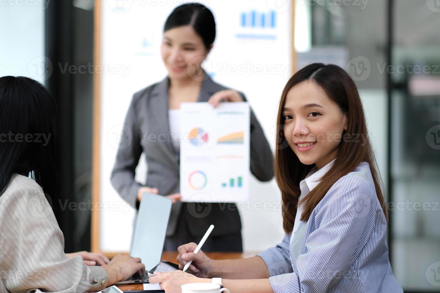 Business. Team meetings. A group sitting down around a table. One person in the foreground. A confident businesswoman photo