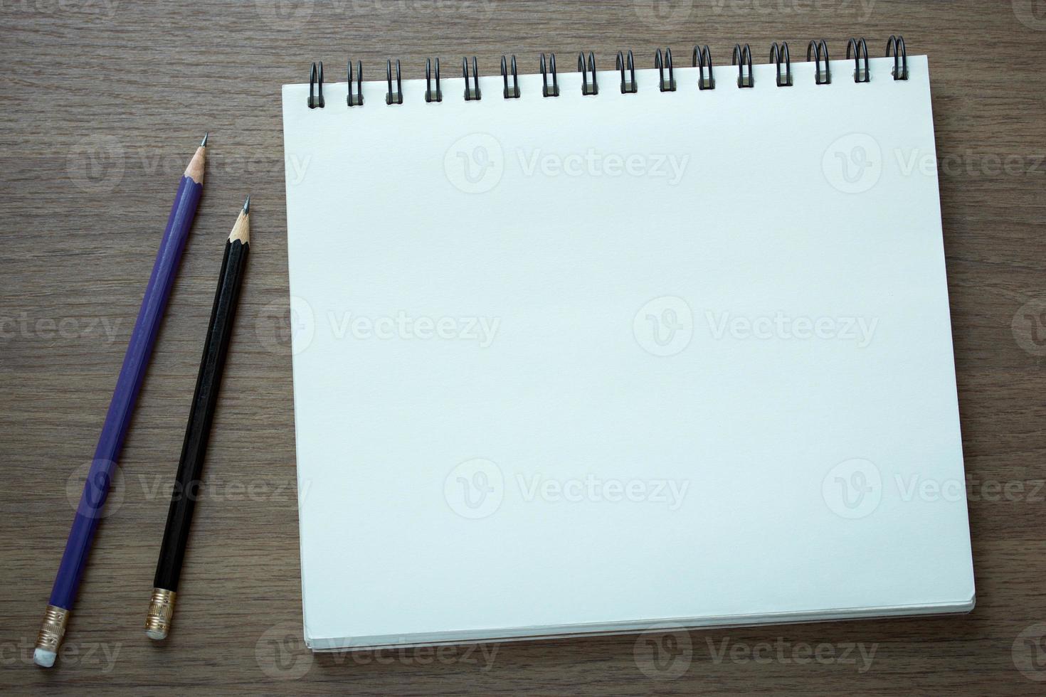 Cuaderno espiral en blanco y lápiz sobre fondo de madera oscura. foto