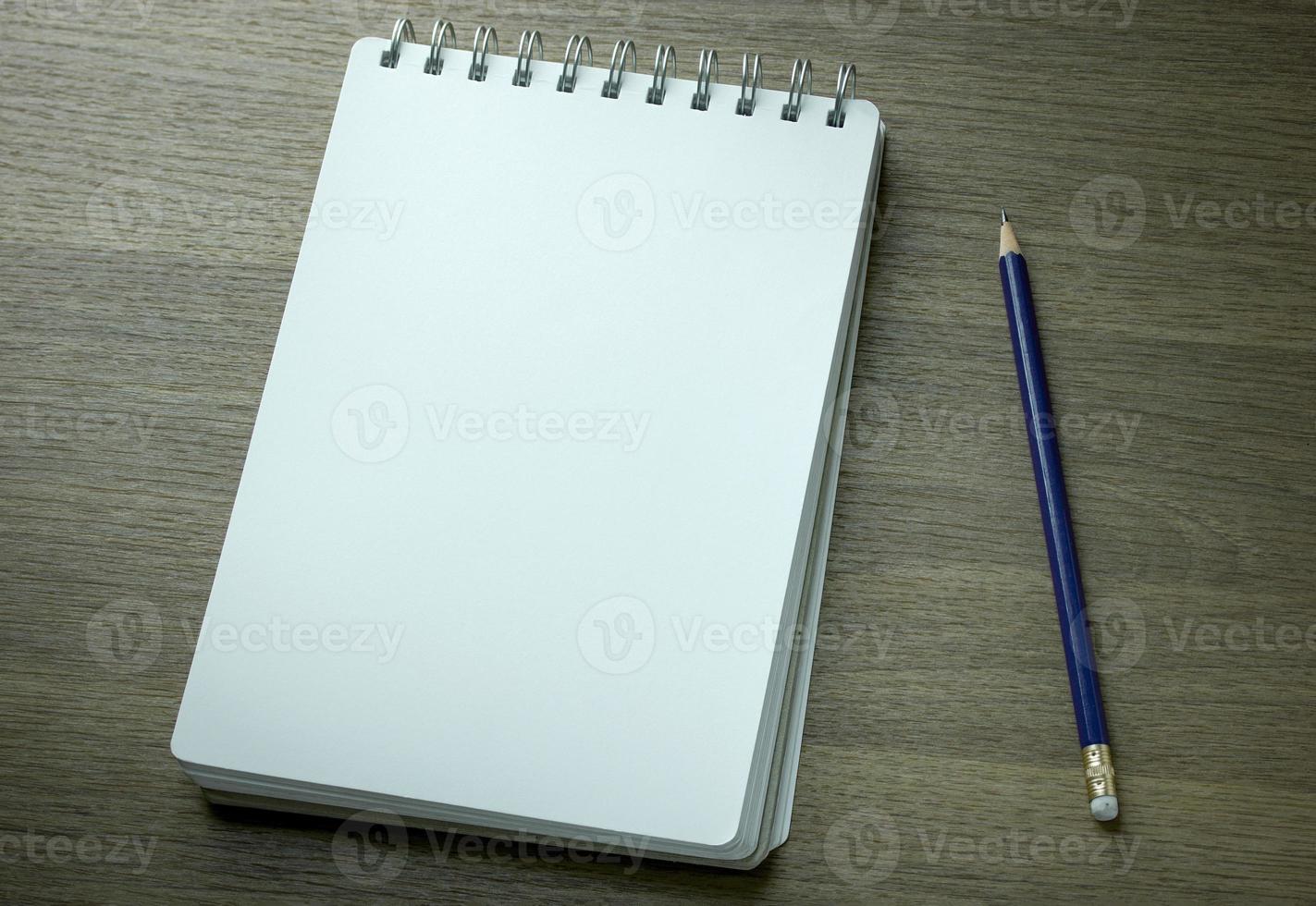 Cuaderno espiral en blanco y lápiz sobre fondo de madera oscura. foto