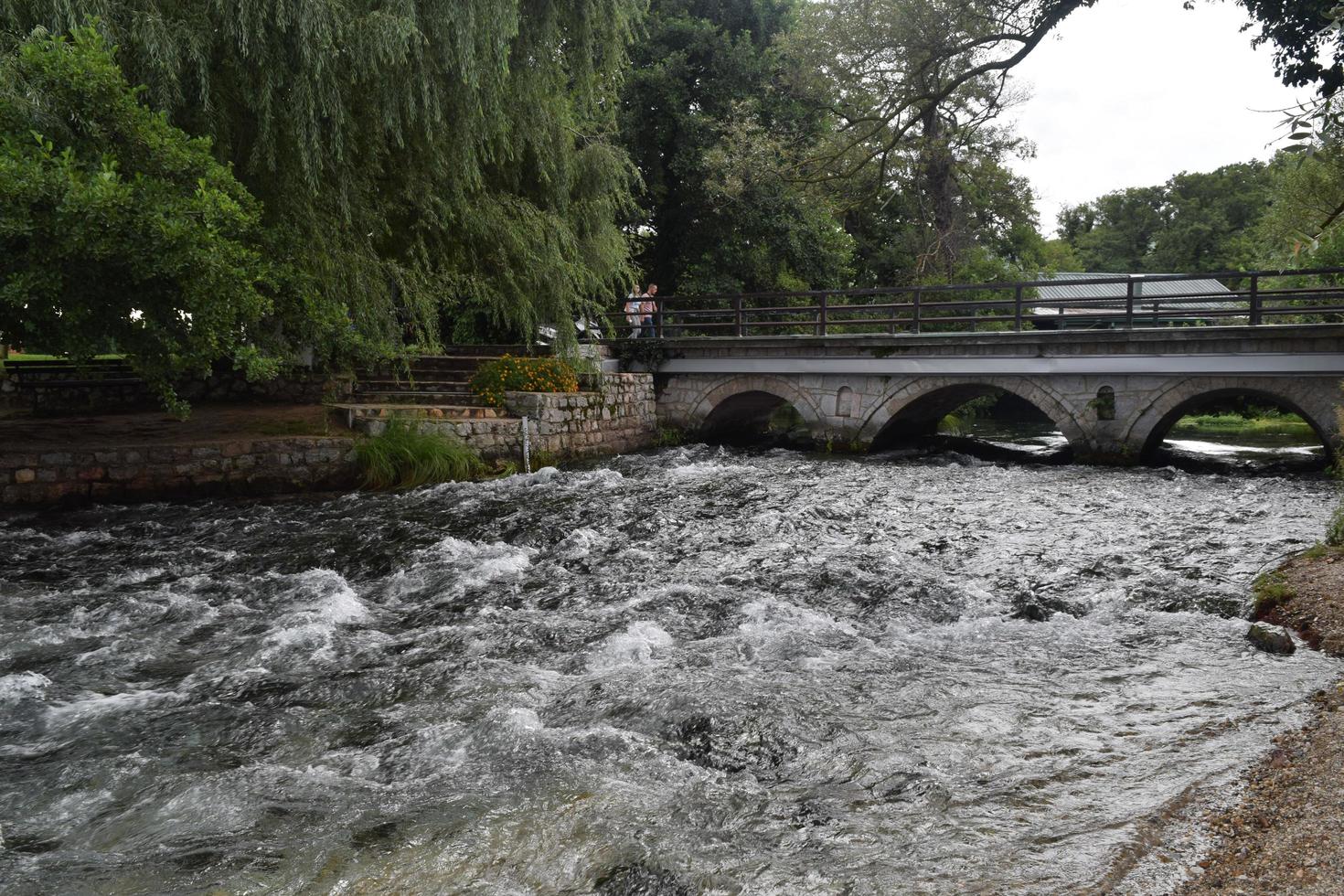 a stormy river flows under an ancient stone bridge photo