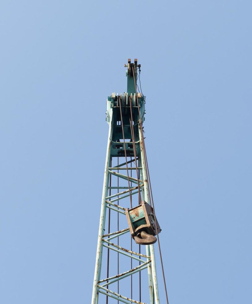 Large green crane boom with hooks with blue sky background photo