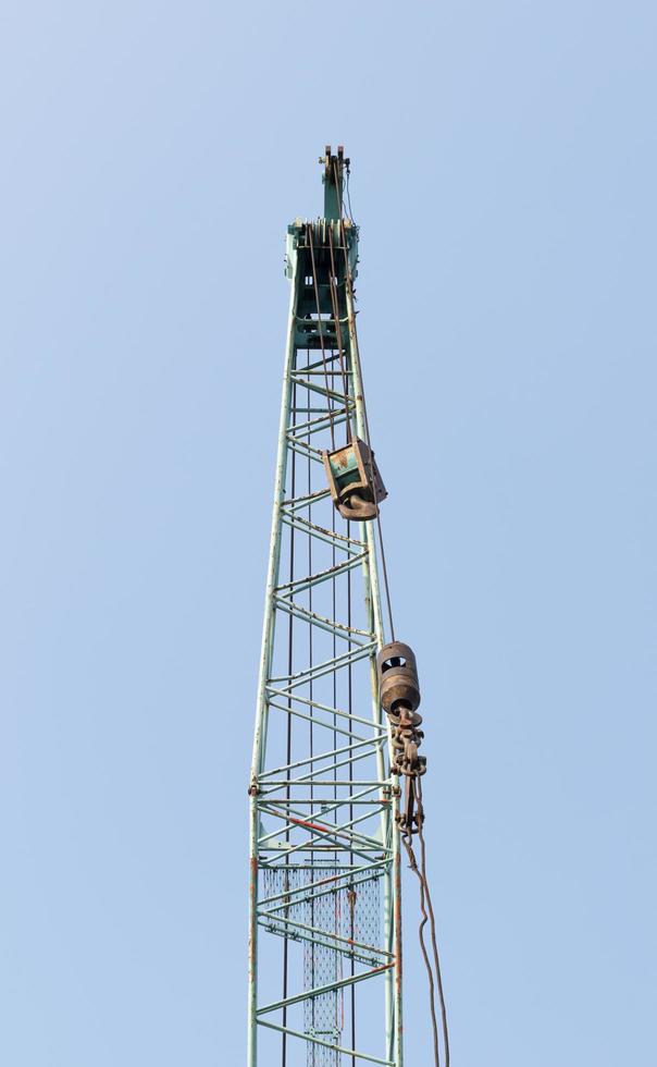 Large green crane boom with hooks with blue sky background photo