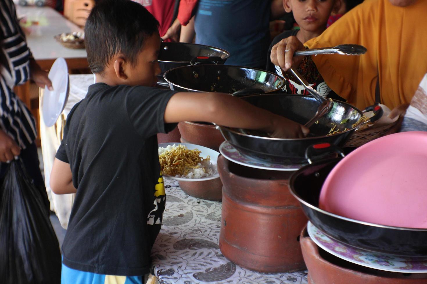 a child is waiting in line for food in front of which there is a large container to put vegetables made of clay.18 03 2022. photo