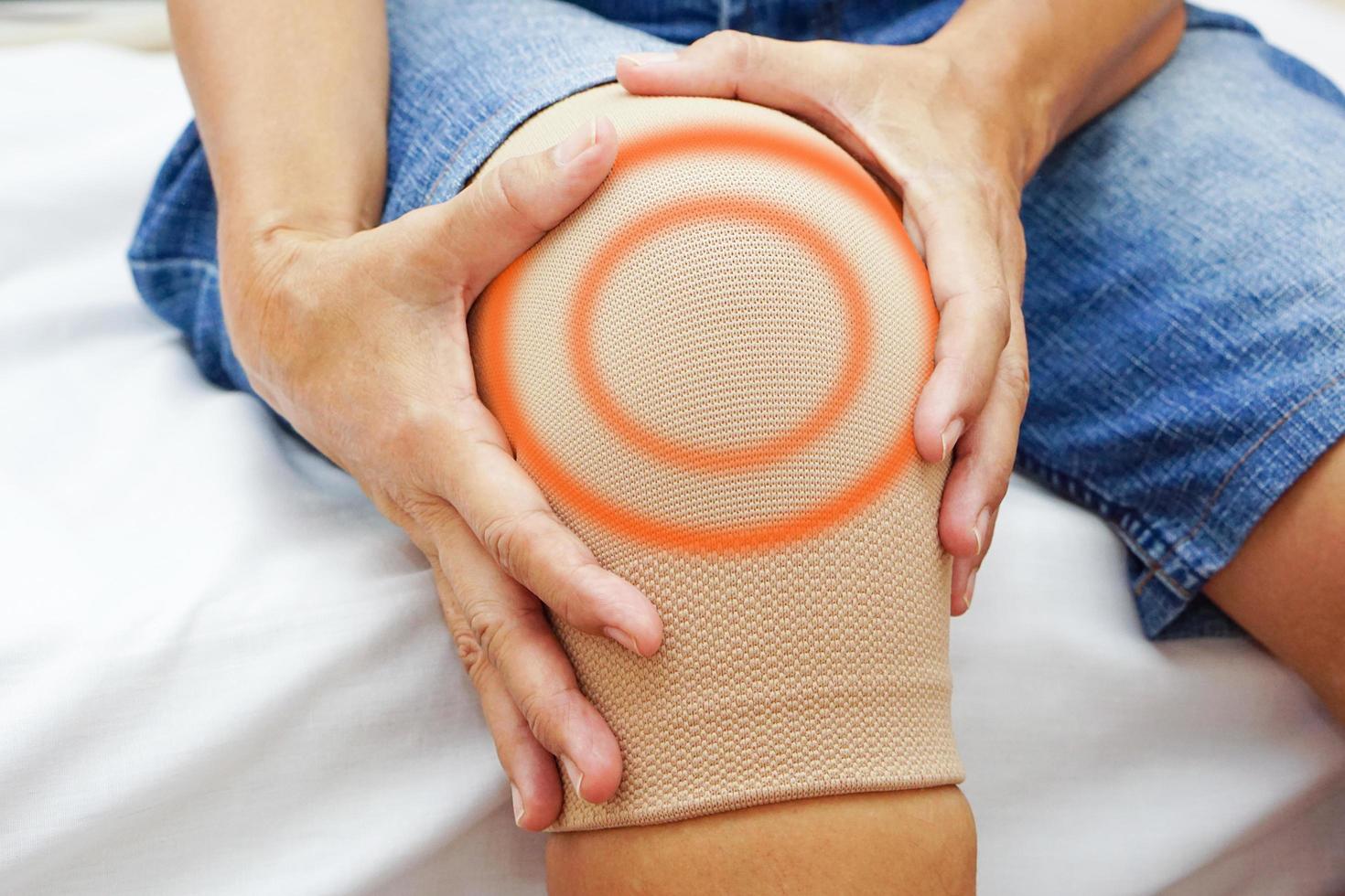 A woman holds her knee with bandage, caused by injury. Concept of Health check, health care and medical. photo