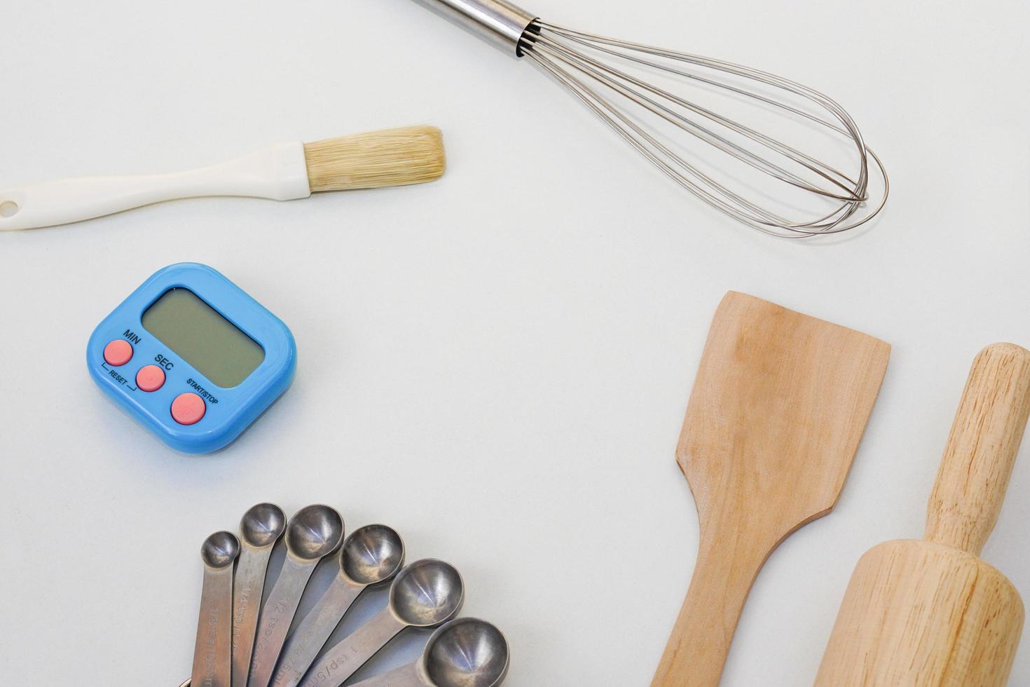 Top view kitchenware wooden rolling pin, wooden spatula and egg beater on white background. photo