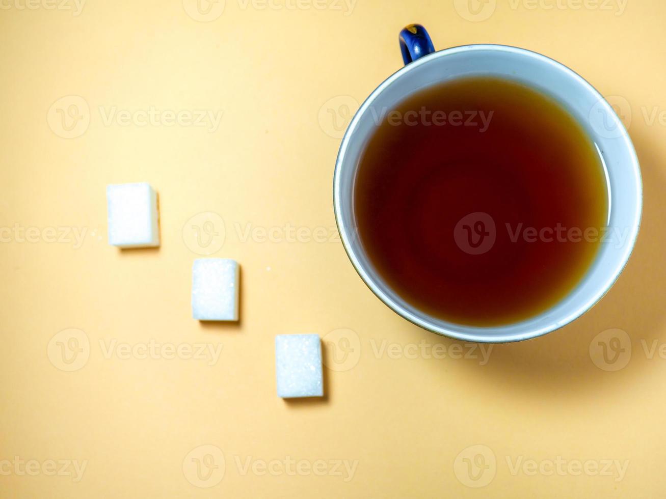 Pieces of sugar a cup of tea on a beige background. Sweet product. photo