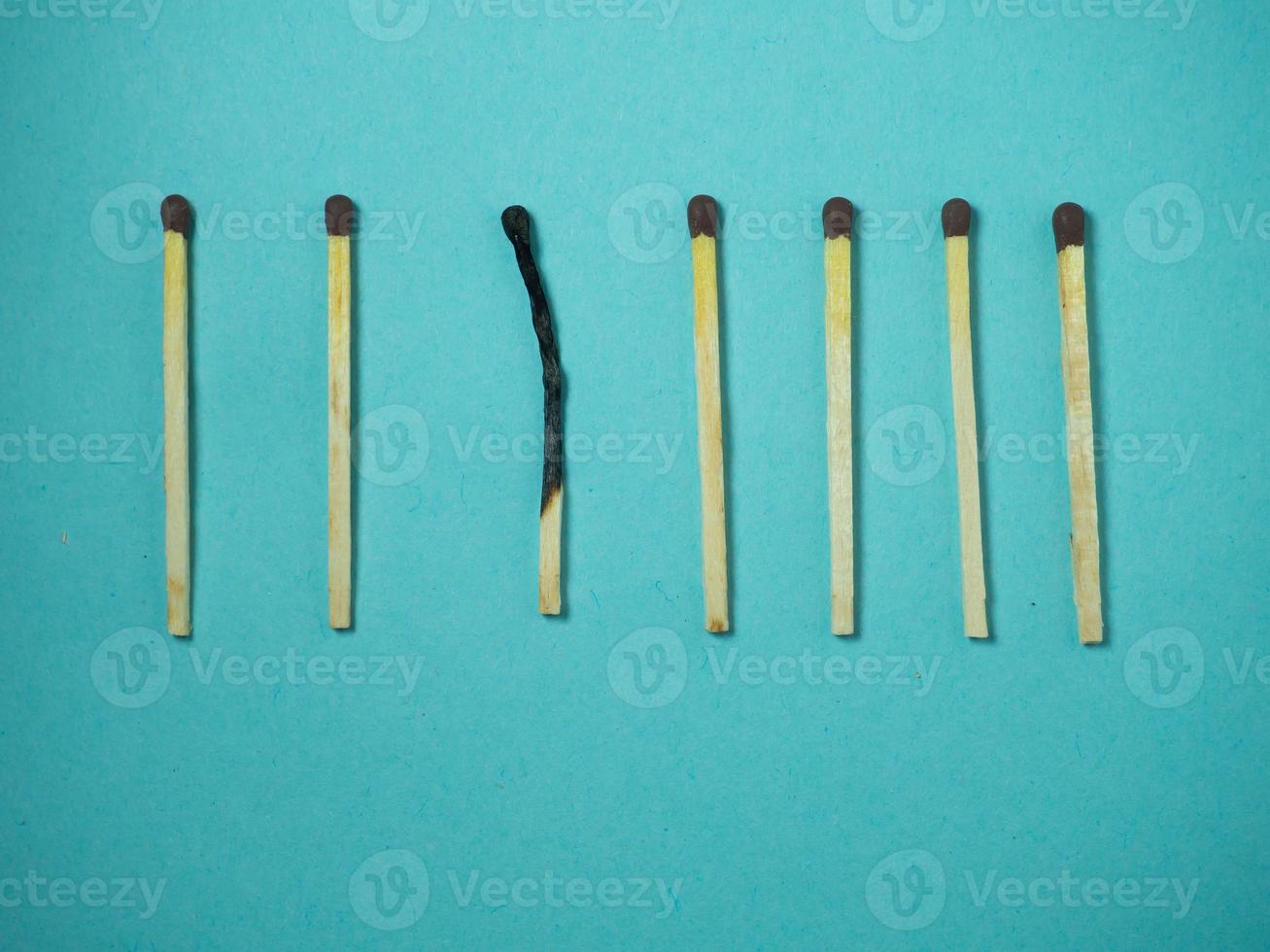 Matches on a blue background.  One against all. Burnt match. photo