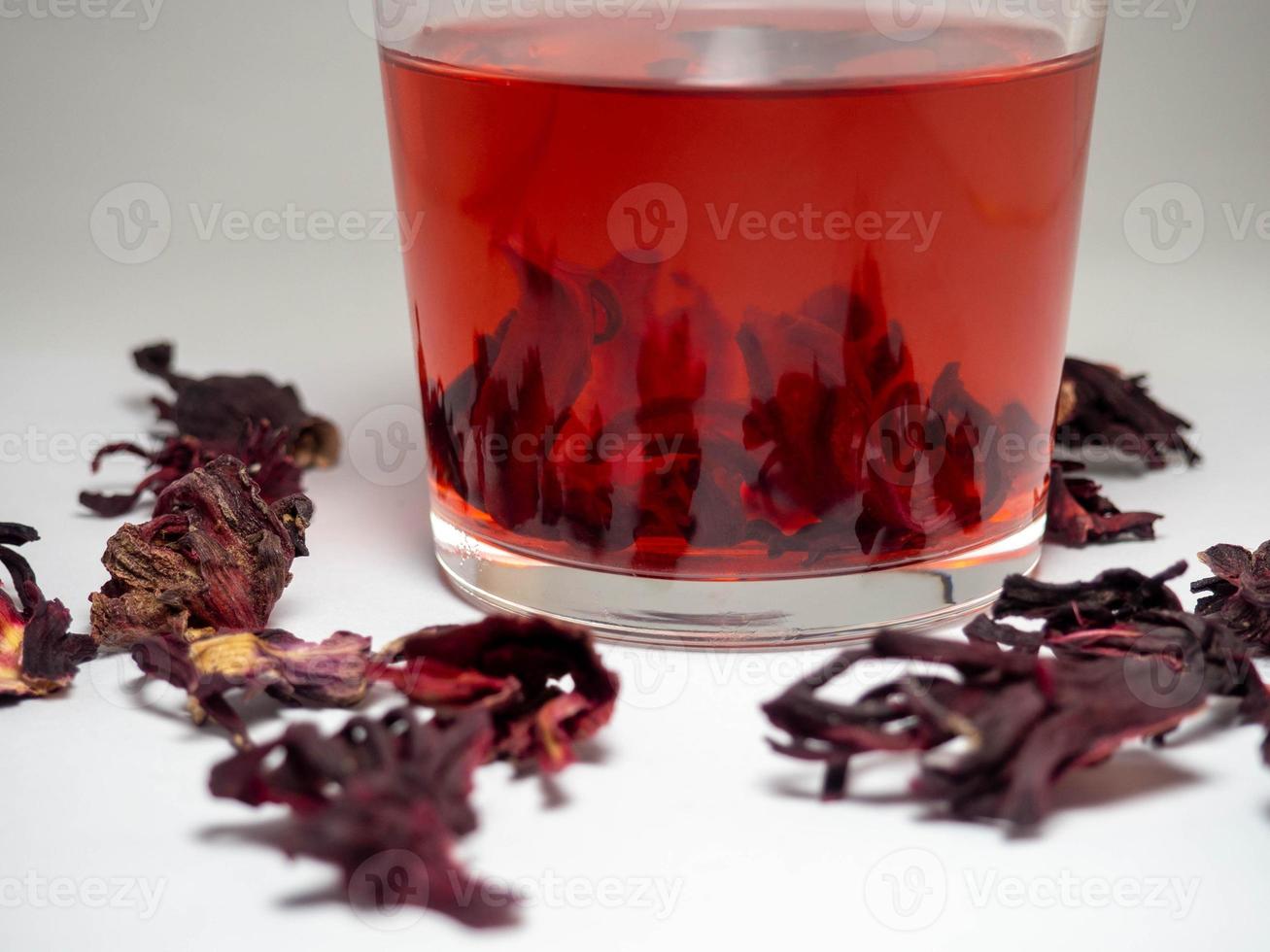 Karkade. Tea drink in a glass. Red liquid in a glass. Dried petals. photo