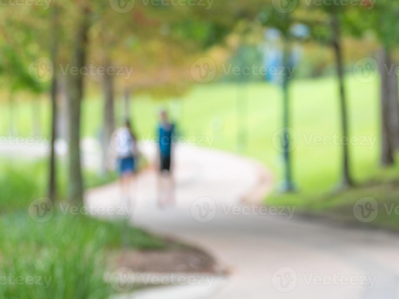 A defocused image of a couple walking on a winding path in the park. photo