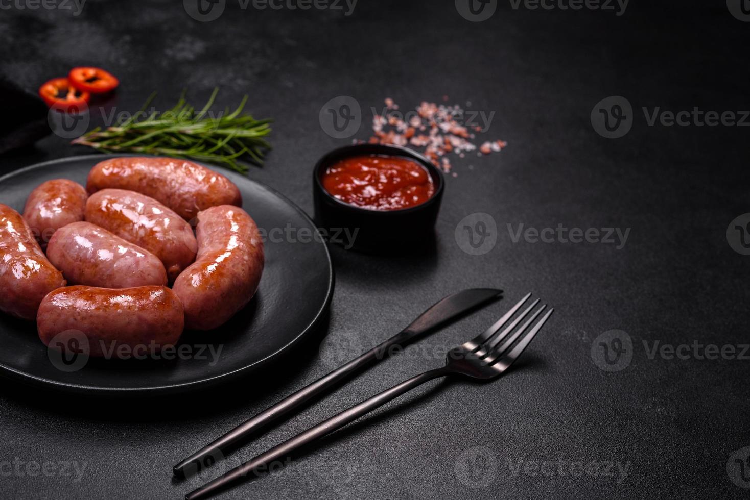 salchichas a la parrilla con especias y hierbas en un fondo negro foto