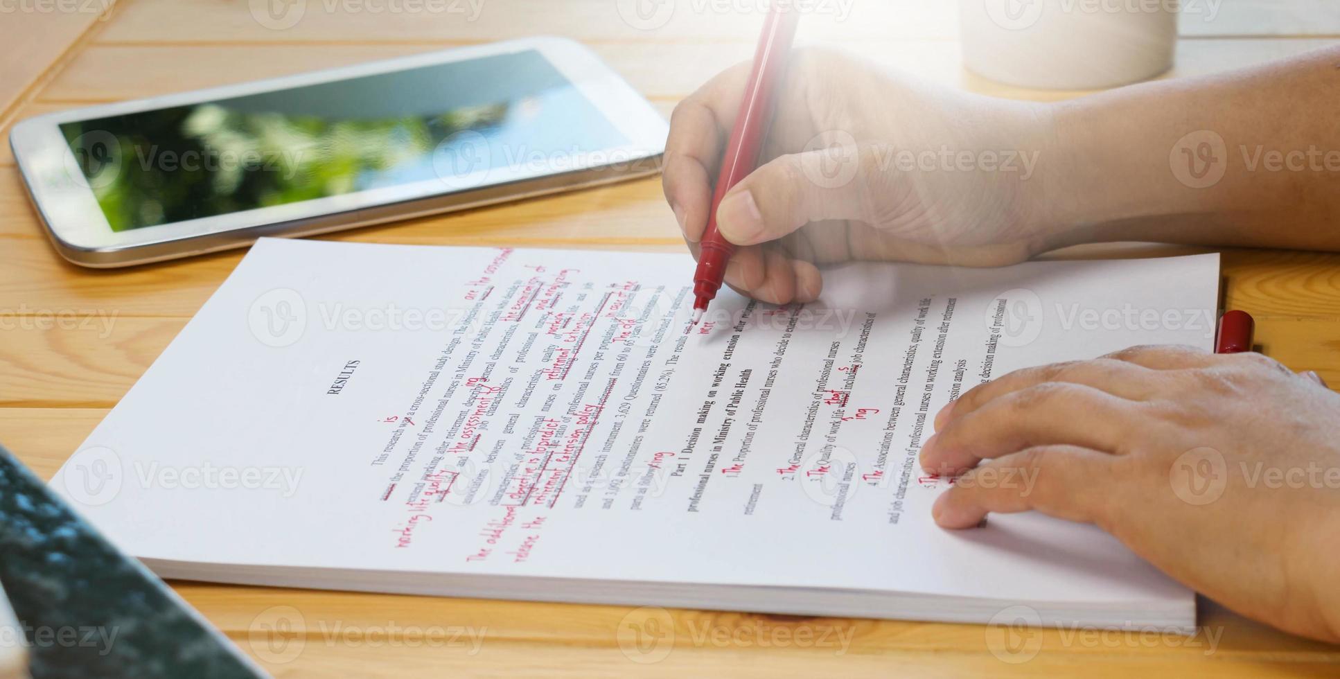 hand holding red pen over proofreading text photo