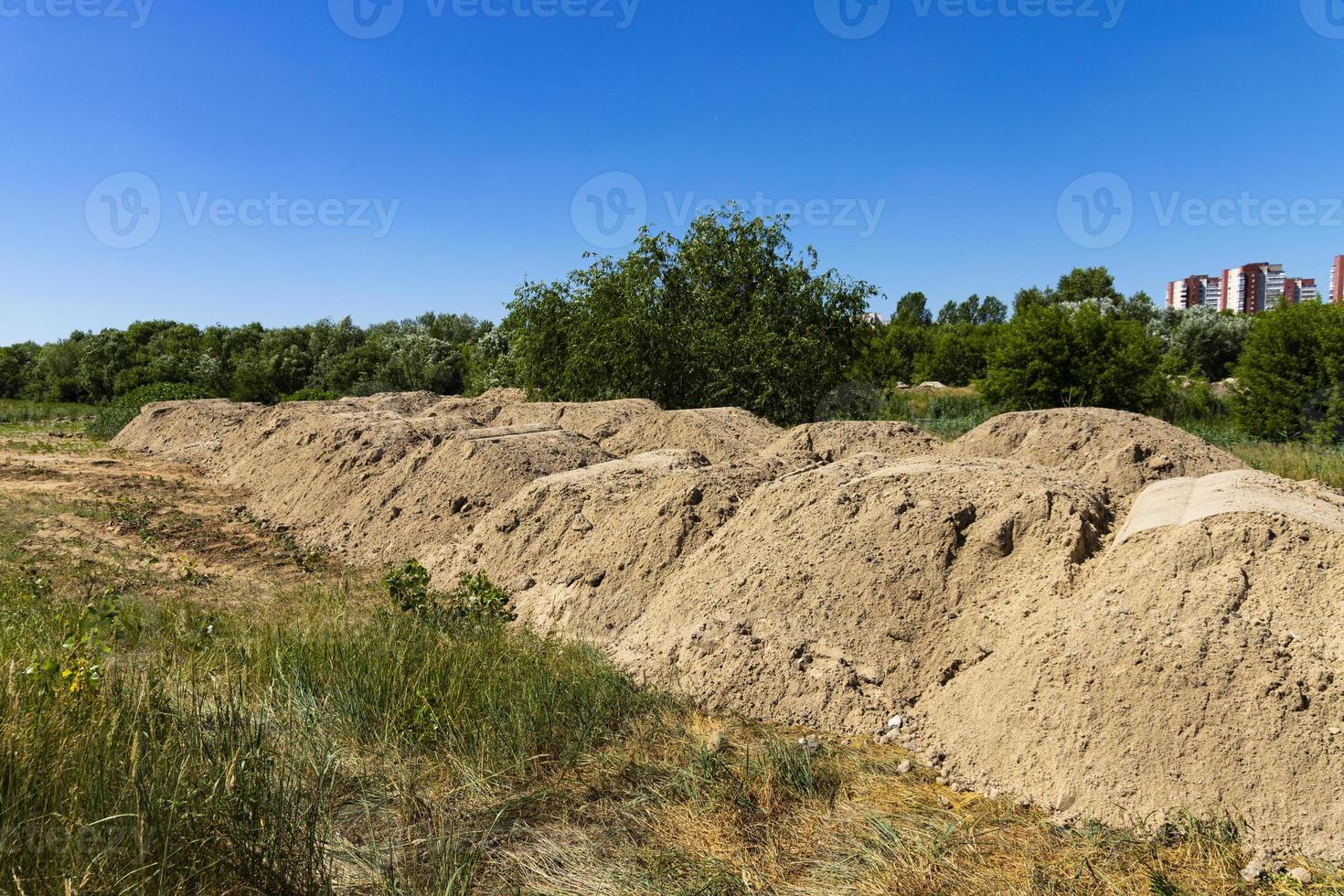 A mountain of sand on a construction site. Foundation material. The soil is prepared to strengthen the soil. Earth heap. Fine sand for leveling and backfilling photo