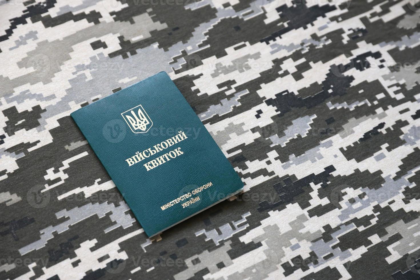 Ukrainian military ID on fabric with texture of pixeled camouflage. Cloth with camo pattern in grey, brown and green pixel shapes with Ukrainian army personal token photo
