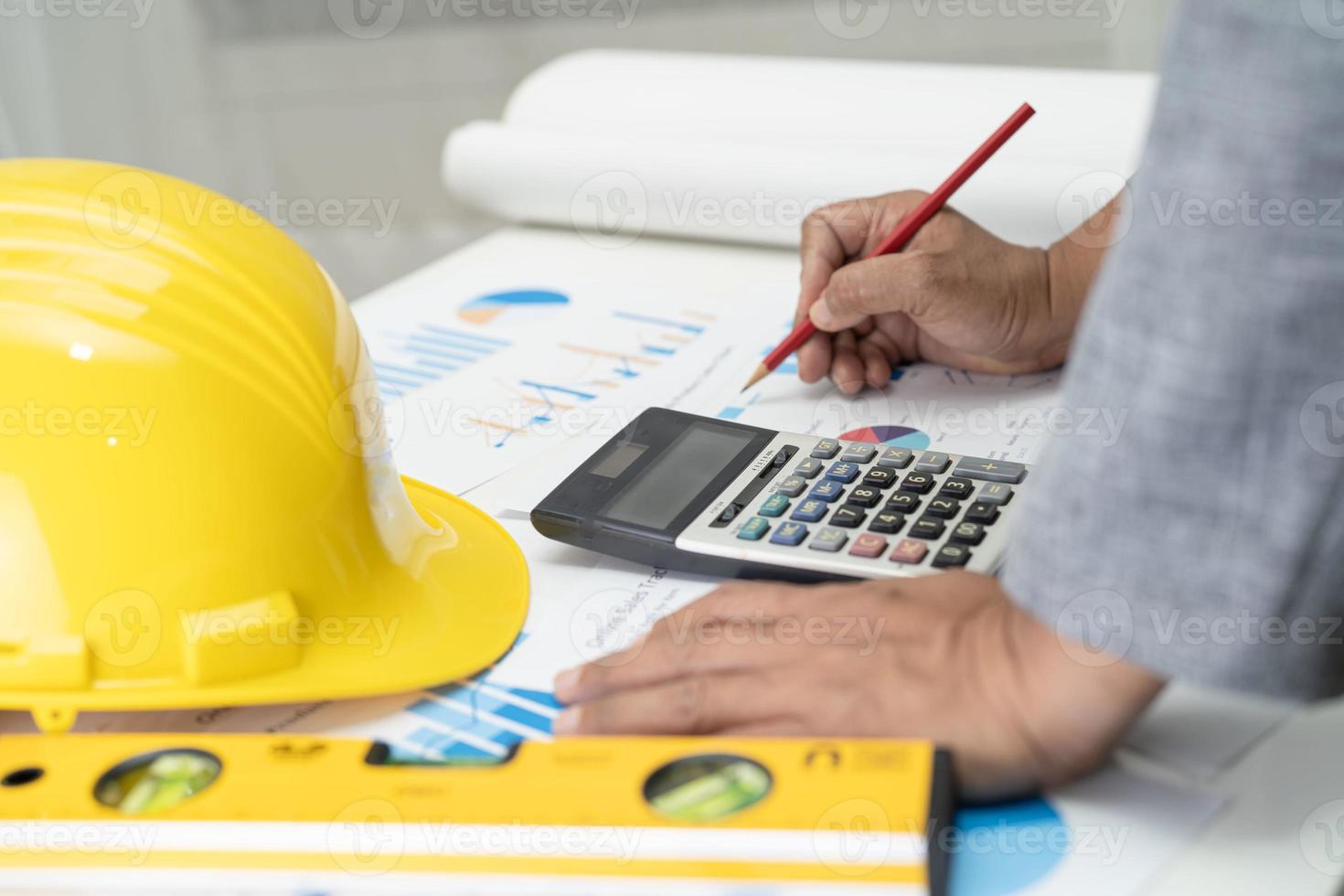 Asian engineer with architectural house plan project blueprint, graph and yellow helmet and engineering construction tools. photo
