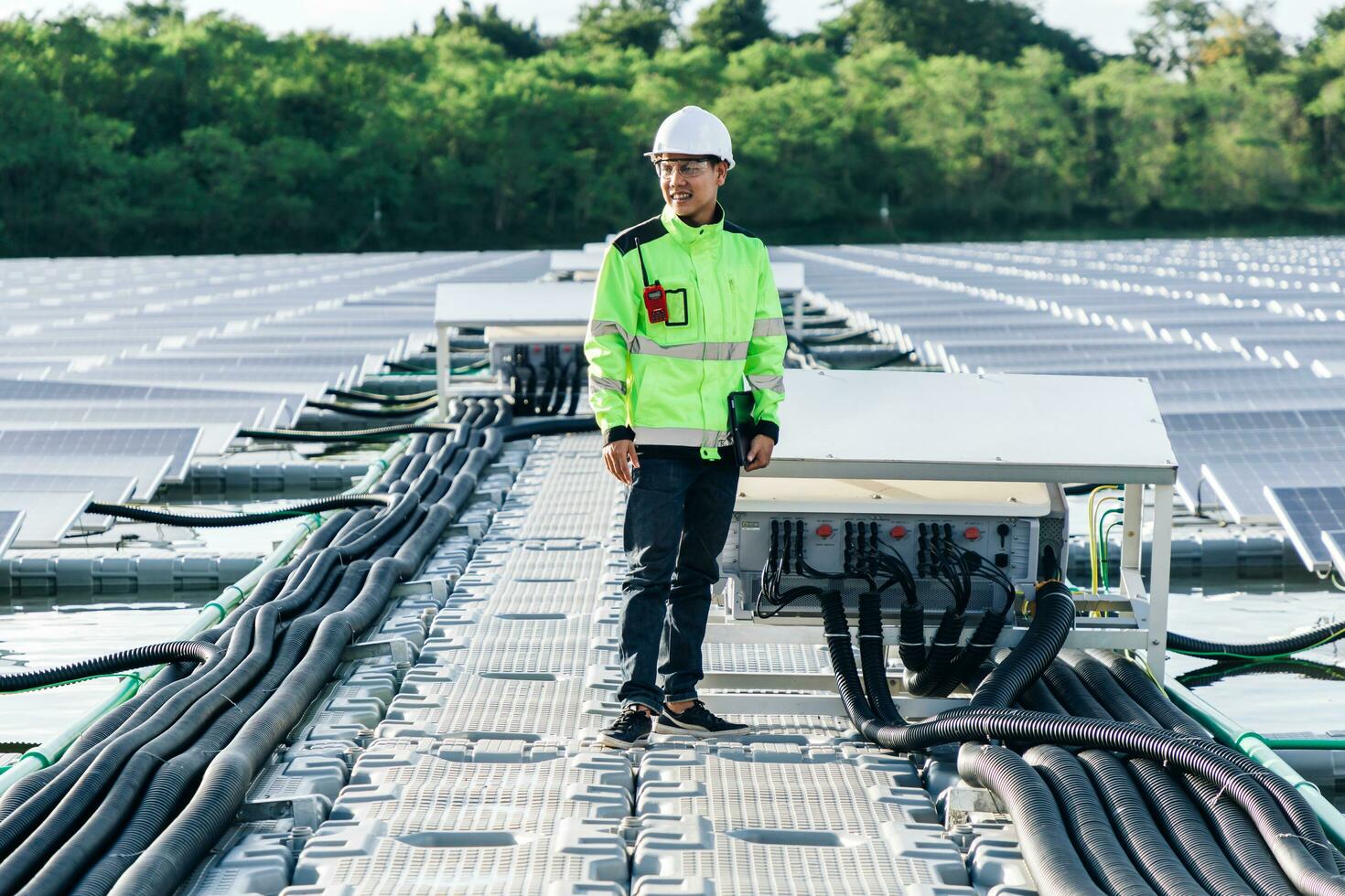Male electrician in white safety helmet standing on ladder and mounting photovoltaic solar panel under beautiful blue sky. Concept of alternative sources of energy. photo