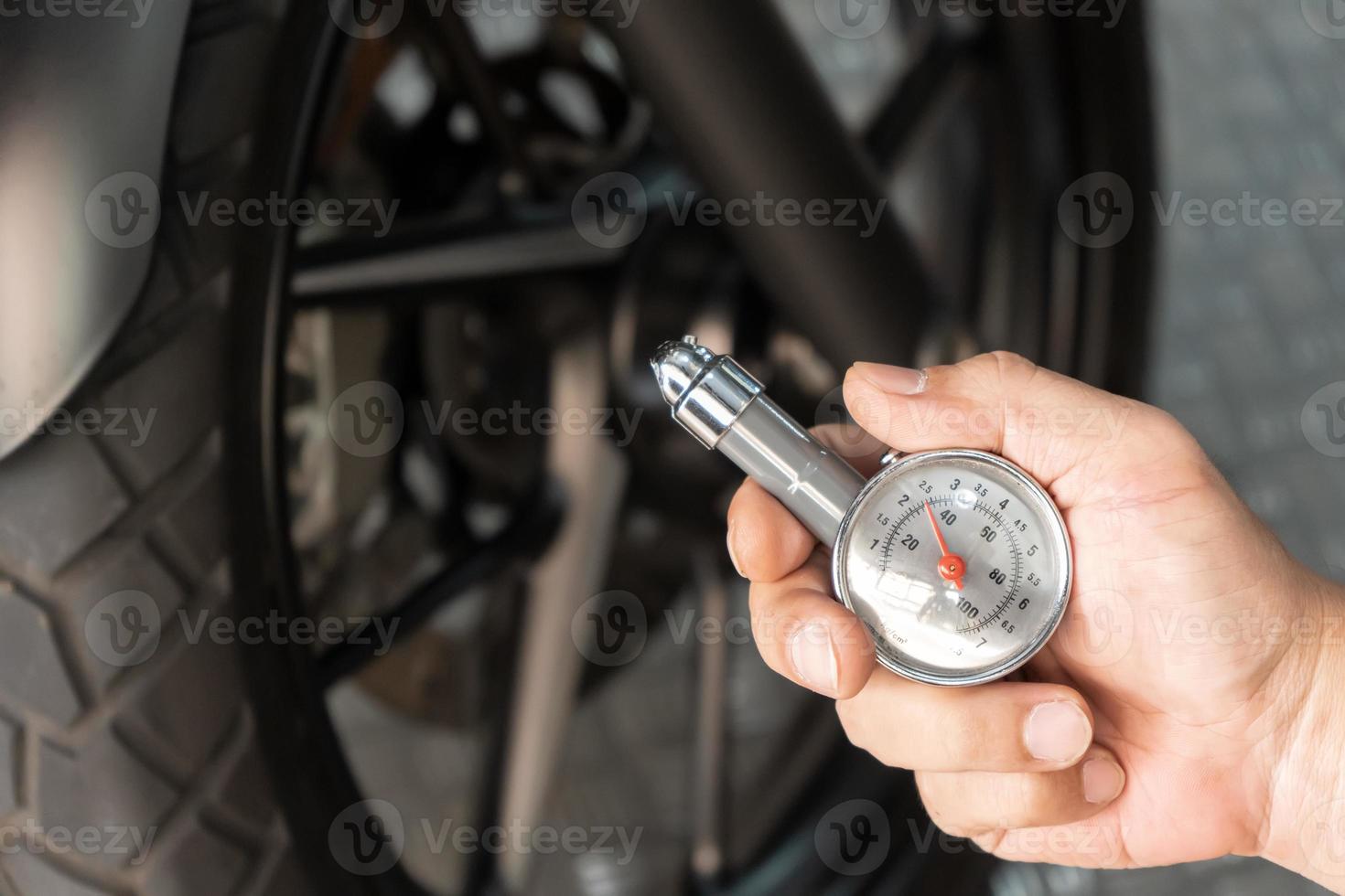 Man holding pressure gauge for checking  motocycle tyre pressure ,maintenance,repair motorcycle concept in garage .selective focus photo