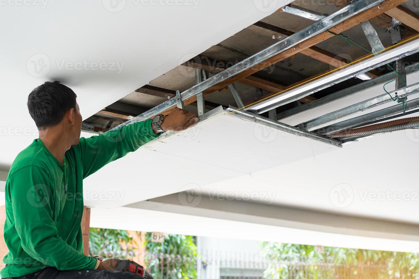 trabajador de techado con uniforme protector y guantes, herramientas para  techos, instalación de techos nuevos en construcción, taladro eléctrico  usado en techos nuevos con láminas de metal. 15632734 Foto de stock en