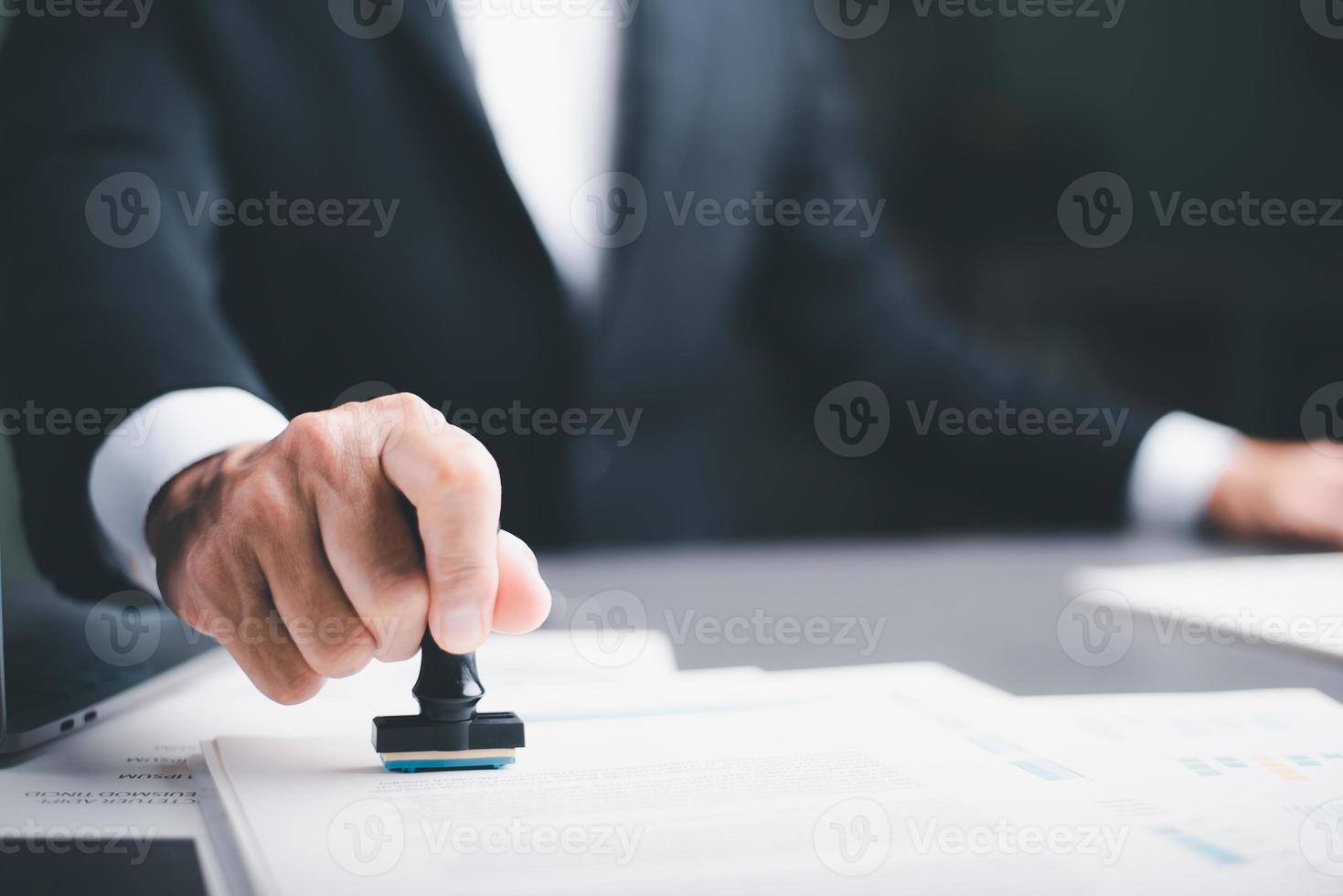 business people stamp On the contract documents at the desk, the concept of confirmation or approval of the agreement, the application authorization authority, the bank loan documents through support. photo