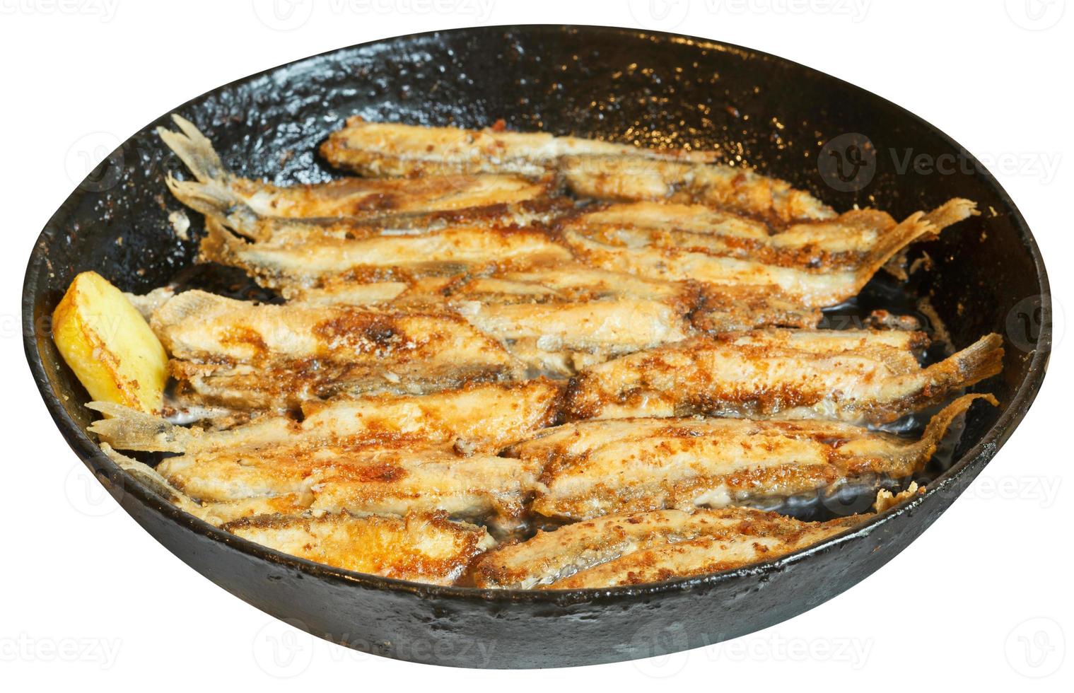 fried fish capelin on black frying pan isolated photo