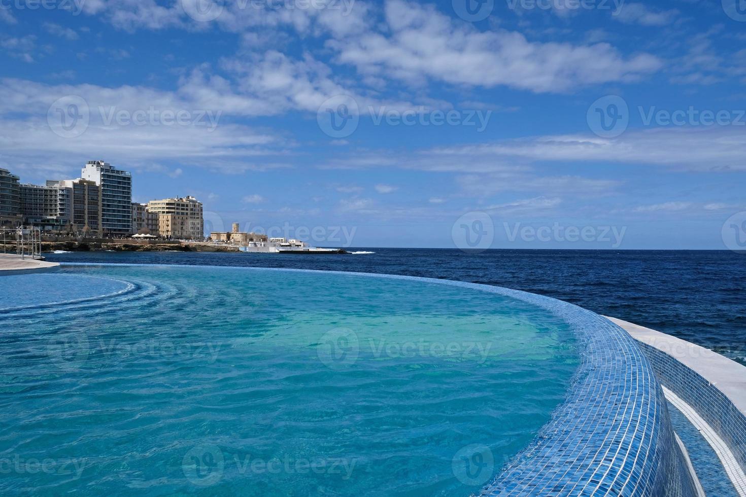 Blue clear water surface in swimming pool in a resort with sea views. Summer Vacation and rest concept. Luxury beach villa house. Blue tile mosaic pattern. photo