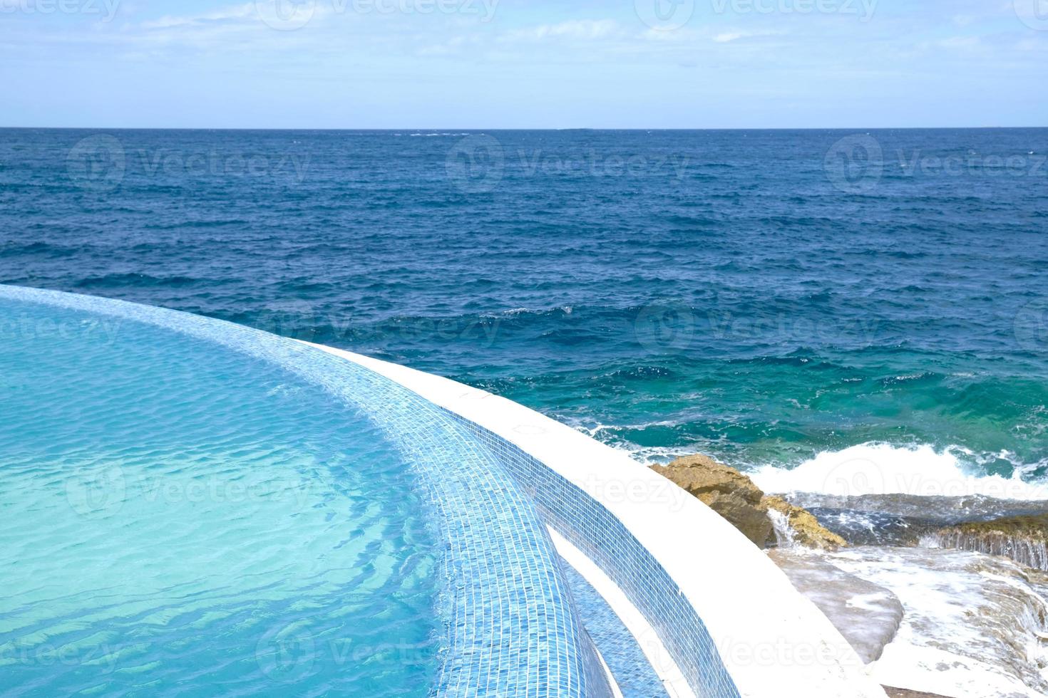 Blue clear water surface in swimming pool in a resort with sea views. Summer Vacation and rest concept. Luxury beach villa house. Blue tile mosaic pattern. photo
