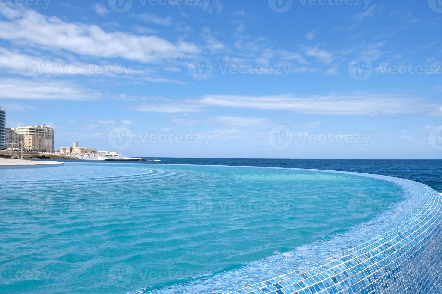 Blue clear water surface in swimming pool in a resort with sea views. Summer Vacation and rest concept. Luxury beach villa house. Blue tile mosaic pattern. photo