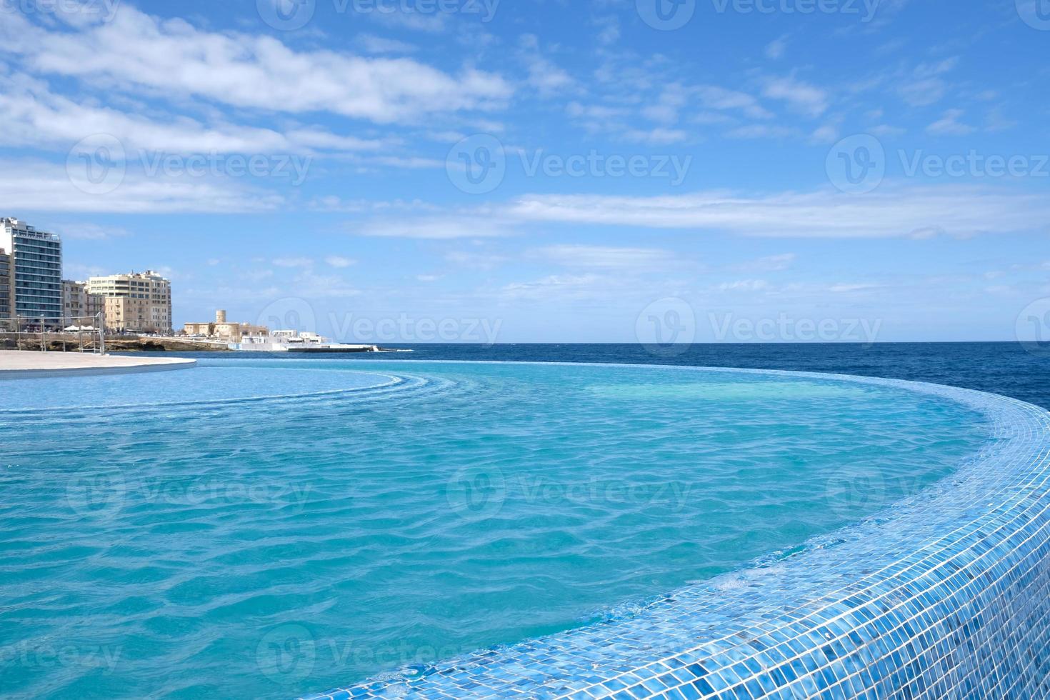 Blue clear water surface in swimming pool in a resort with sea views. Summer Vacation and rest concept. Luxury beach villa house. Blue tile mosaic pattern. photo