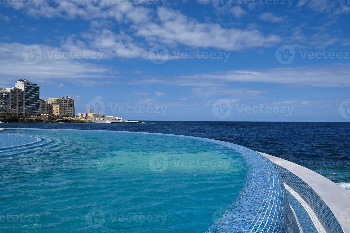 Blue clear water surface in swimming pool in a resort with sea views. Summer Vacation and rest concept. Luxury beach villa house. Blue tile mosaic pattern. photo